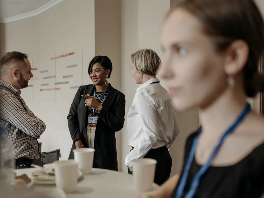 Professionals with lanyards talking over coffee