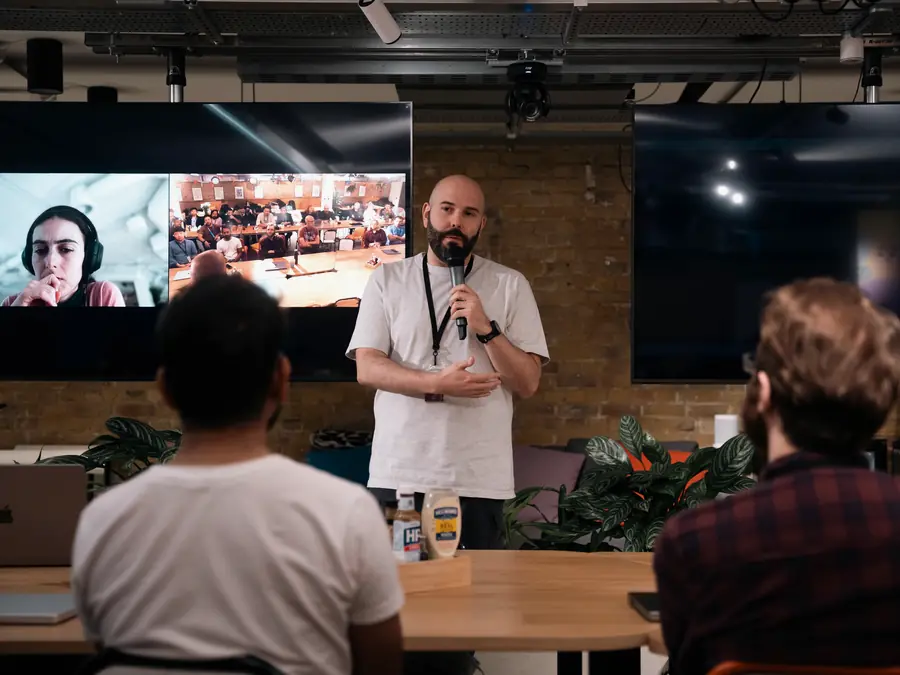 A presenter with a microphone speaking to a small room
